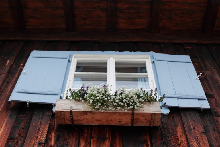 Hingucker: Das Almbad Sillberghaus mit blauen Fensterläden und Blumenkasten